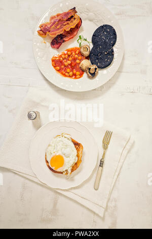 Inglese fry up colazione sulla piastra bianca e rustico sfondo. Vista superiore Foto Stock