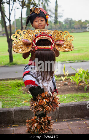 Bali, Indonesia - 23 Giugno 2018: ragazzo ballerino in costumi etnici con maschera tradizionale Balinese di buono spirito Barong sulla cerimonia Indù Ngelawang Foto Stock