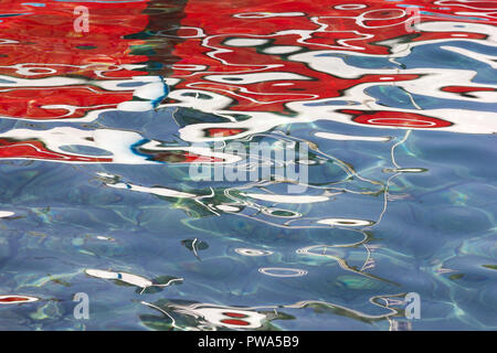 Una immagine astratta di una barca rossa riflessa nell'acqua Foto Stock