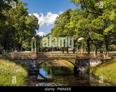 Il ponte di pietra con gazebo e vasi in stile cinese sul canale vicino al vicolo con lussureggianti alberi verdi in Alexander Park a Carskoe Selo Foto Stock