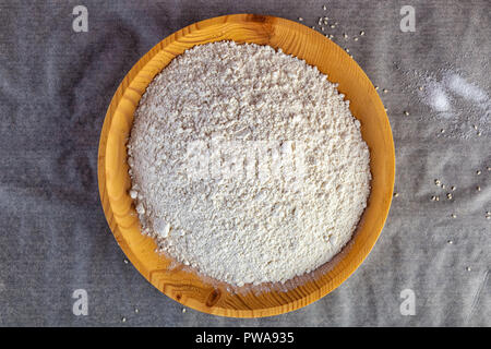 Close-up di friabile farina di frumento bianca in un piatto di legno sul tavolo della cucina.Flat laici. Foto Stock