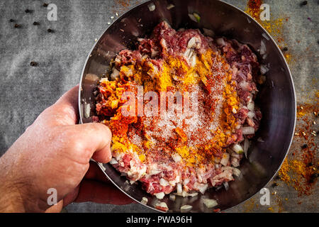 Il processo di cottura delle polpette di carne, hamburger, lasagne e altri piatti a base di carne. Piatto: laici ciotola di ingredienti miscelati per le polpette di carne:carni bovine, cipolla, aglio Foto Stock