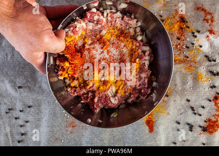 Il processo di cottura delle polpette di carne, hamburger, lasagne e altri piatti a base di carne. Piatto: laici ciotola di ingredienti miscelati per le polpette di carne:carni bovine, cipolla, aglio Foto Stock