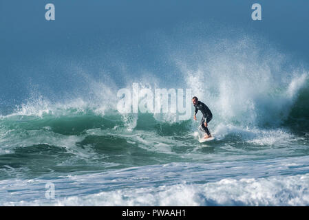 Un surfista in sella a una grande onda a Fistral a Newquay in Cornovaglia. Foto Stock