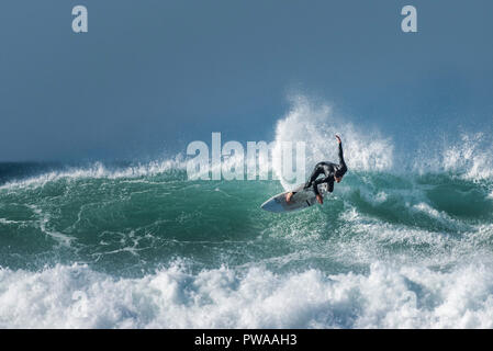 Un surfista in sella a una grande onda a Fistral a Newquay in Cornovaglia. Foto Stock