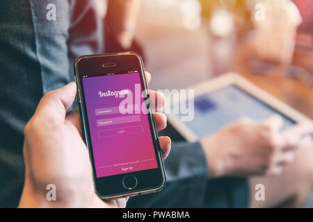 Instagram app su iPhone con persone con background tablet closeup maschio di tenere in mano la rete sociale sul dispositivo intelligente concetto.23 Settembre 2018,Bangkok Th Foto Stock