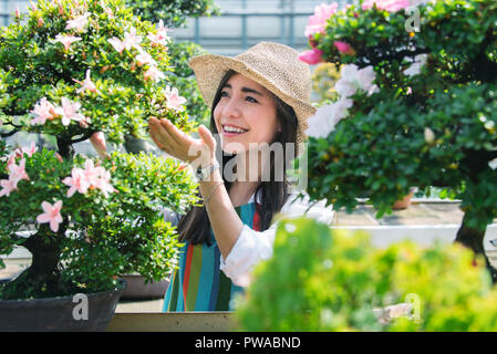 Bella femmina giardiniere di prendersi cura di piante in suoi fiori e piante shop - donna asiatica lavora in una serra Foto Stock