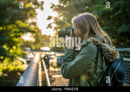 Giovane donna è scattare una foto dalla natura durante il tramonto Foto Stock