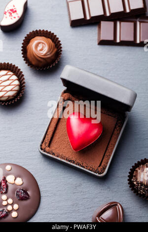 Al cioccolato a forma di cuore candy in una confezione regalo su sfondo di ardesia. Vista superiore Foto Stock