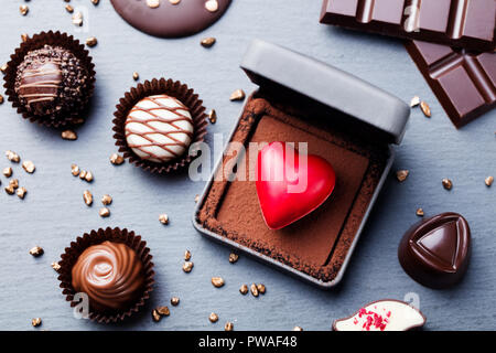 Al cioccolato a forma di cuore candy in una confezione regalo su sfondo di ardesia. Vista superiore Foto Stock