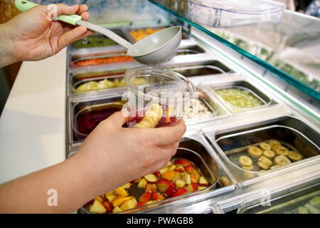 Varie La frutta fresca e insalata di verdure bar prodotti sani. Mano è la preparazione di frutti per il frullato di organico. Afferrando la frutta tagliata con la siviera e la messa. Foto Stock