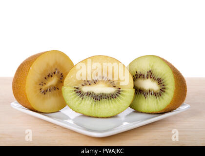 Kiwi e sungold kiwi tagliate a metà due tipi fuse su piastra bianca sulla tavola di legno. I kiwi, o uva spina cinese è la bacca commestibile Foto Stock