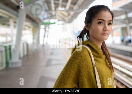 Giovane bella donna asiatica in attesa treno in corrispondenza della piattaforma Foto Stock