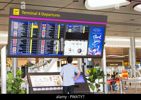 Man controlla l'orario di partenza del sistema di visualizzazione delle informazioni sui voli delle compagnie aeree Changi Airport Terminal 4. Il T4 è l'aeroporto più recente, aperto nel 2018. Foto Stock