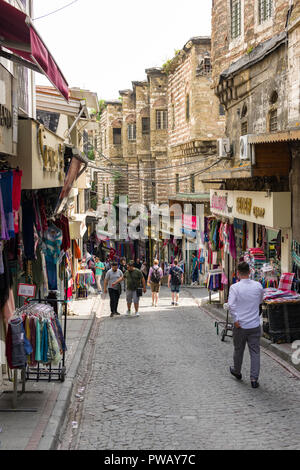 File di negozi con merci sulla linea di visualizzazione una zona collinare strada di ciottoli con cittadini e turisti a piedi lungo di esso nel distretto di Fatih, Istanbul, Turchia Foto Stock