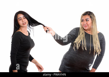 Grasso di giovane donna asiatica tira i capelli di Asian transgender donna Foto Stock