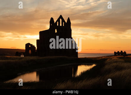 Silhouette abbazia... Come il sole estivo inizia ad impostare dietro il Whitby Abbey una splendida silhouette è creato. Foto Stock