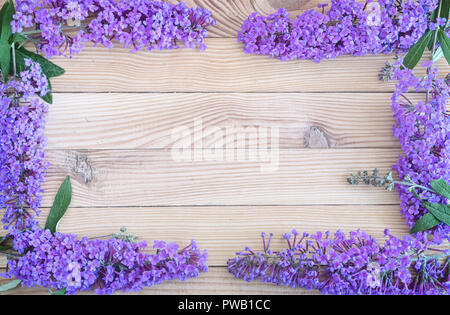 Bella infiorescenza arbusto decorativo buddleja Davidii, costituito da numerosi piccoli fiori lilla su una luce sullo sfondo di legno. Disposti in un telaio. Foto Stock