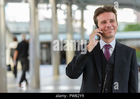 Happy businessman premuroso sorridente e parlando al telefono cellulare Foto Stock