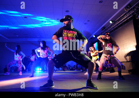 Gli istruttori dancing energicamente sul palco durante una classe Zumba Foto Stock