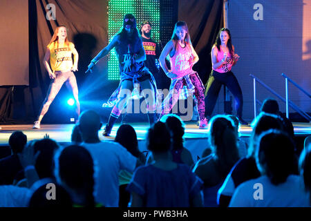 Gli istruttori dancing energicamente sul palco durante una classe Zumba Foto Stock
