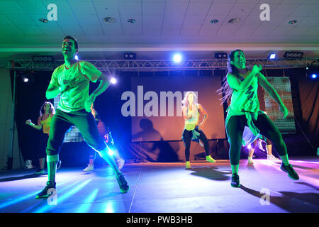 Gli istruttori dancing energicamente sul palco durante una classe Zumba Foto Stock