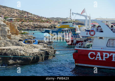 Escursione barche ormeggiate a rocce in laguna blu, l'isola di Comino e Malta, per consentire la loro vacanzieri di nuotare e tuffarsi nelle acque cristalline di Foto Stock