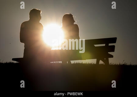 Oberwiesenthal, in Sassonia. Xiv oct, 2018. Un uomo e una donna seduti su una panchina di Oberwiesenthal contro la luce del sole di sera. Credito: Jan Woitas/dpa-Zentralbild/dpa/Alamy Live News Foto Stock
