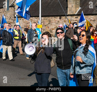 Donna con megafono e gruppo ridere tutti sotto uno striscione AUOB indipendenza scozzese marzo 2018, Royal Mile di Edimburgo, Scozia, Regno Unito Foto Stock