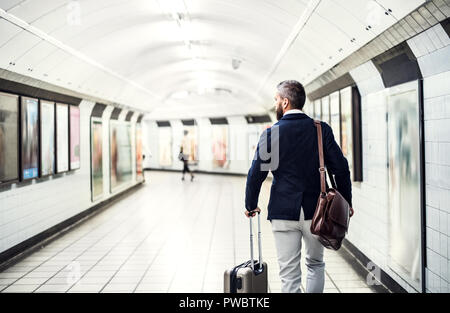 Vista posteriore di imprenditore con un sacchetto e valigia camminando in metropolitana. Copia dello spazio. Foto Stock