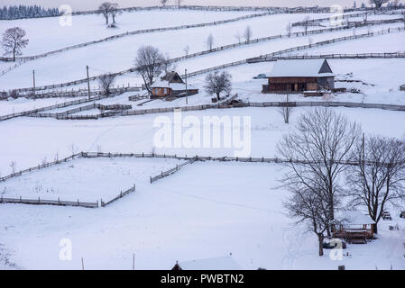 Villaggio alpino in Transilvania, Romania. Coperta di neve case in inverno Foto Stock