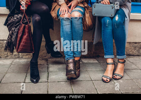 Tre donne che indossano scarpe alla moda, abbigliamento e accessori esterni. Bellezza fashion concept. Foto Stock