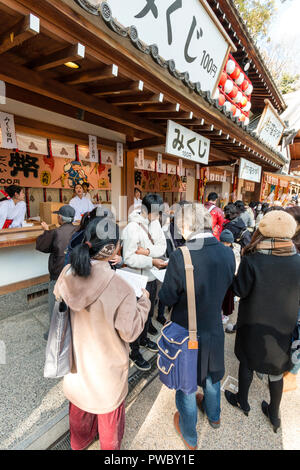 Giapponese anno nuovo, shogatsu. Persone in piedi dal santuario di lettura contatore Omikuji fortune carta scivola presso la popolare Nishinomiya santuario. Foto Stock