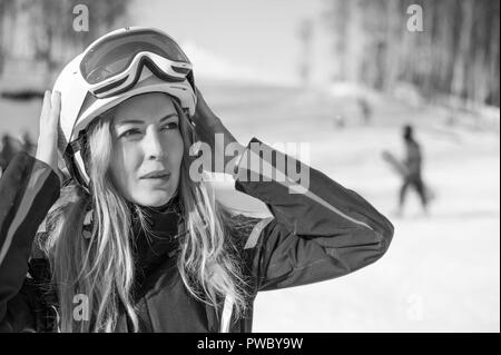 Giovane donna adulta snowboarder o sciatore close up ritratto indossando healmet bianco con maschera in neve montagna invernale Foto Stock