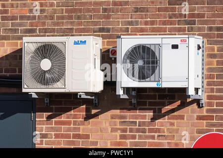 Coppia di commerciali di piccole dimensioni di condensazione ad aria unità di refrigerazione per shop aria condizionata montato su una parete esterna del Regno Unito. Foto Stock