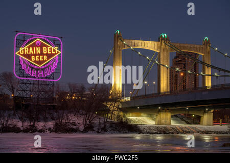 Storico cinghia grano segno di birra e di Hennepin Avenue ponte lungo il fiume Mississippi nel centro di Minneapolis, Minnesota. Il segno è accesa in viola e Foto Stock