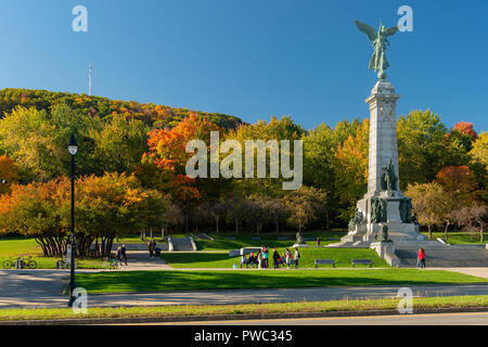 Montreal, Canada - 14 Ottobre 2018: Mont-Royal fogliame burst con colori autunnali, come le persone che sono in piedi accanto a George-Etienne Cartier monumento. Foto Stock