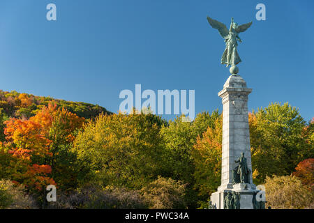 Montreal, Canada - 14 Ottobre 2018: Mont-Royal fogliame burst con colori autunnali, come le persone che sono in piedi accanto a George-Etienne Cartier monumento. Foto Stock