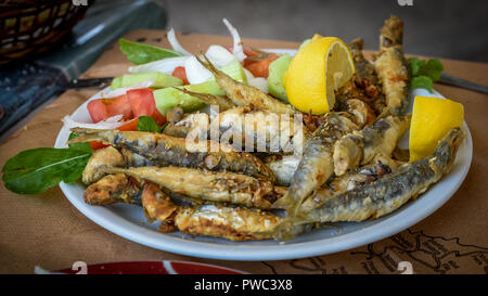Fried puzzava di pesce su una piastra con insalata Foto Stock