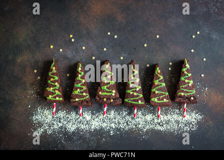 Brownie al cioccolato a forma di alberi di Natale con la glassa verde e festosa spruzzino, vista dall'alto, copia dello spazio. Dolce Natale o vacanze invernali pasticceria Foto Stock