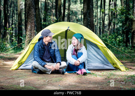 Ritratto di asian giovane seduto e parlare su la tenda da campeggio Foto Stock