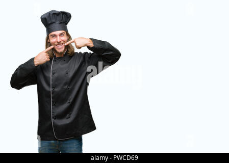 Bel giovane cuoco uomo con capelli lunghi su sfondo isolato sorridente fiducioso che mostra e indicando con le dita dei denti e della bocca. Concetto di salute. Foto Stock