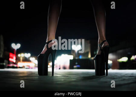 Vista ravvicinata di gambe femmina indossando scarpe su un tacco alto. Donna in piedi sul ponte in serata e in attesa. Scarpe con i tacchi alti per eseguire su SAN Foto Stock