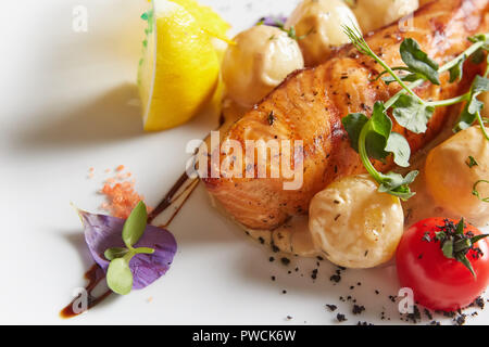 Salmone arrosto con patate su piastra bianca. Dof poco profondo Foto Stock