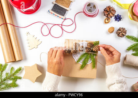 Regalo di natale di avvolgimento. Donna di mani imballaggio regali di Natale sul tavolo bianco Foto Stock