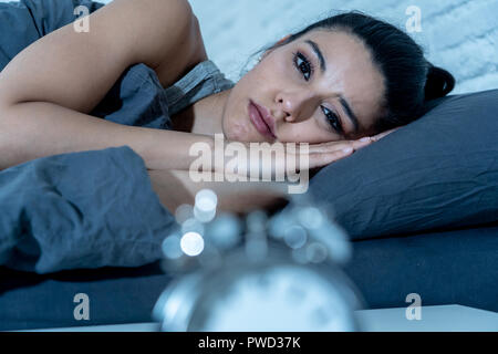 Insonne e disperato bella donna latina sveglio di notte non è in grado di dormire guardando l'orologio che soffrono di insonnia in disturbo del sonno concetto. Foto Stock
