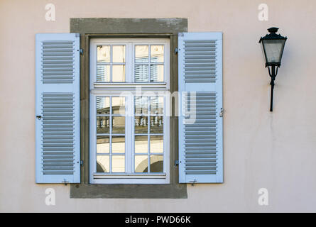 La riflessione di un edificio storico in un vecchio, in legno finestra blu su una parete bianca Foto Stock