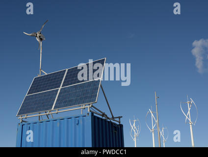 Quattro pannelli solari e piccola turbina eolica montati su container blu per la spedizione, generazione di energia eolica e solare per apparecchiature di monitoraggio costiero uk Foto Stock