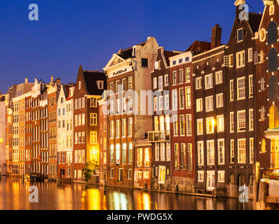 Case di Amsterdam su Damrak Illuminato illuminato di notte case con architettura olandese dal canal Amsterdam Olanda Paesi Bassi EU Europe Foto Stock