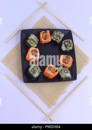 Diversi tipi di maki sushi su una piastra nera Foto Stock